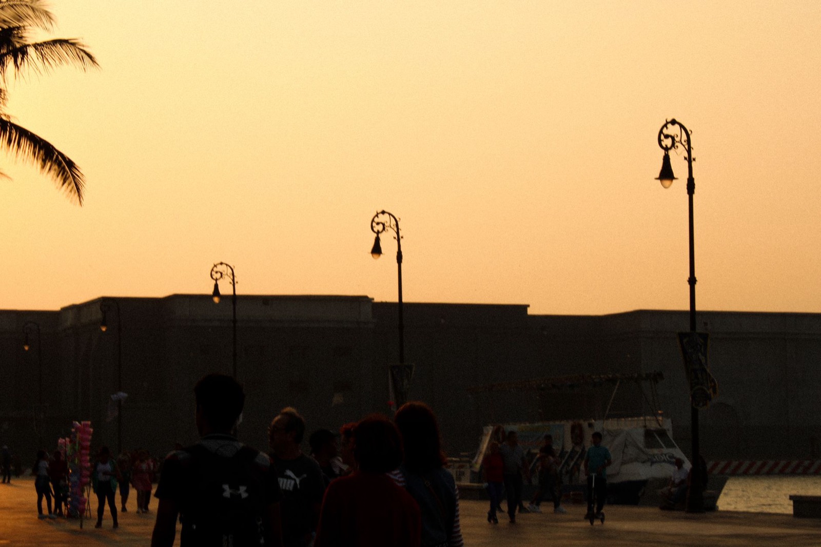Promeneurs sur un quai au coucher du soleil, au bord d'un port méditerranéen
