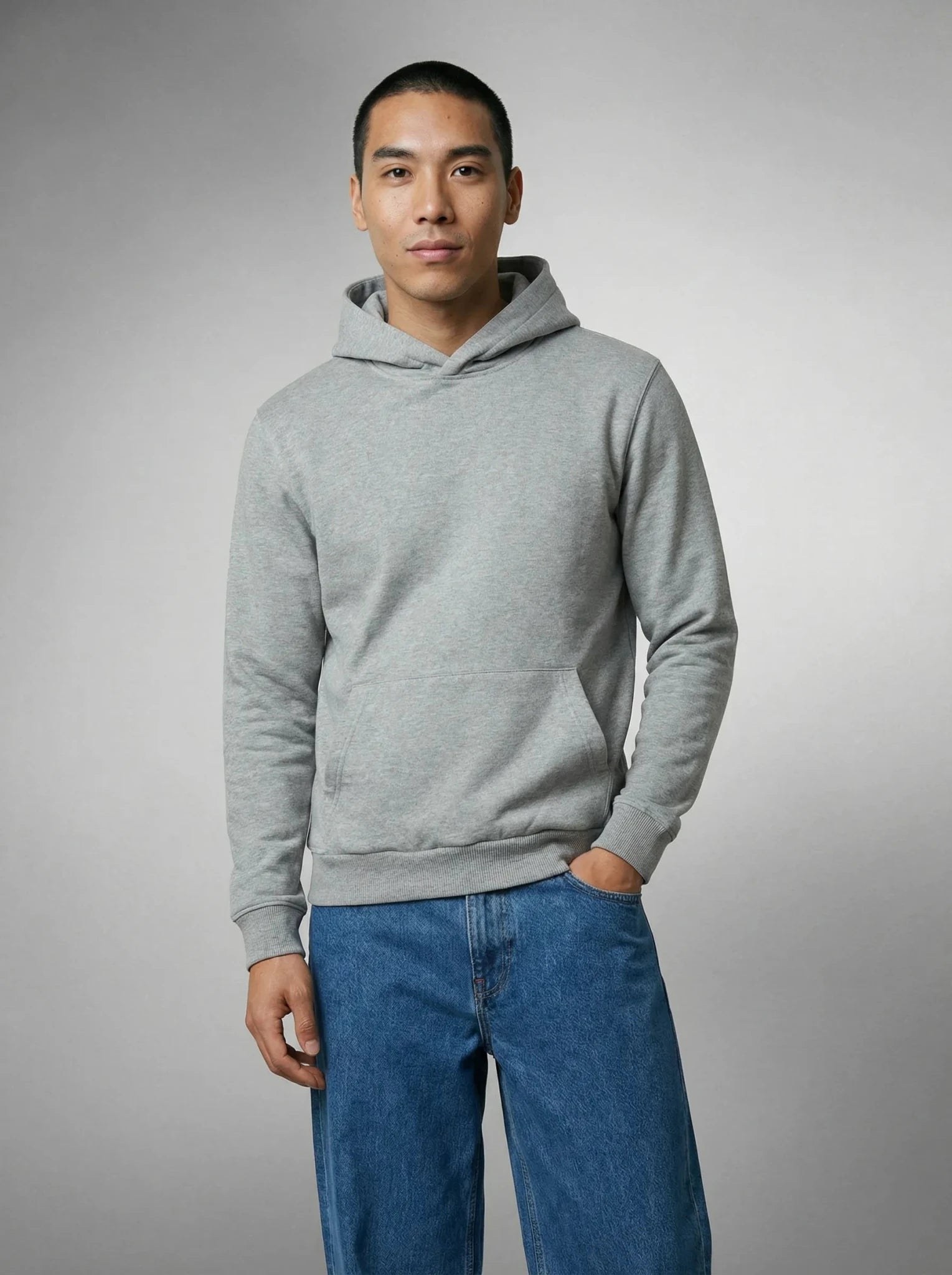 Homme en sweat à capuche gris épais, main dans la poche, sur jean bleu